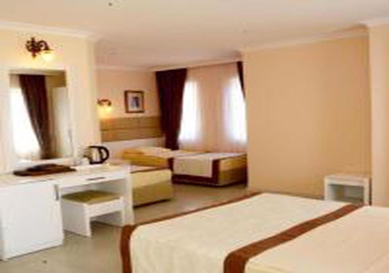 Miramor Hotel & Spa Antalya Luaran gambar The photo shows a hotel room with two beds and a cozy, inviting atmosphere. One bed is larger, possibly a queen or king size, and is draped with a light-colored bedspread that has a brown accent. The room has light-colored walls and natural light str